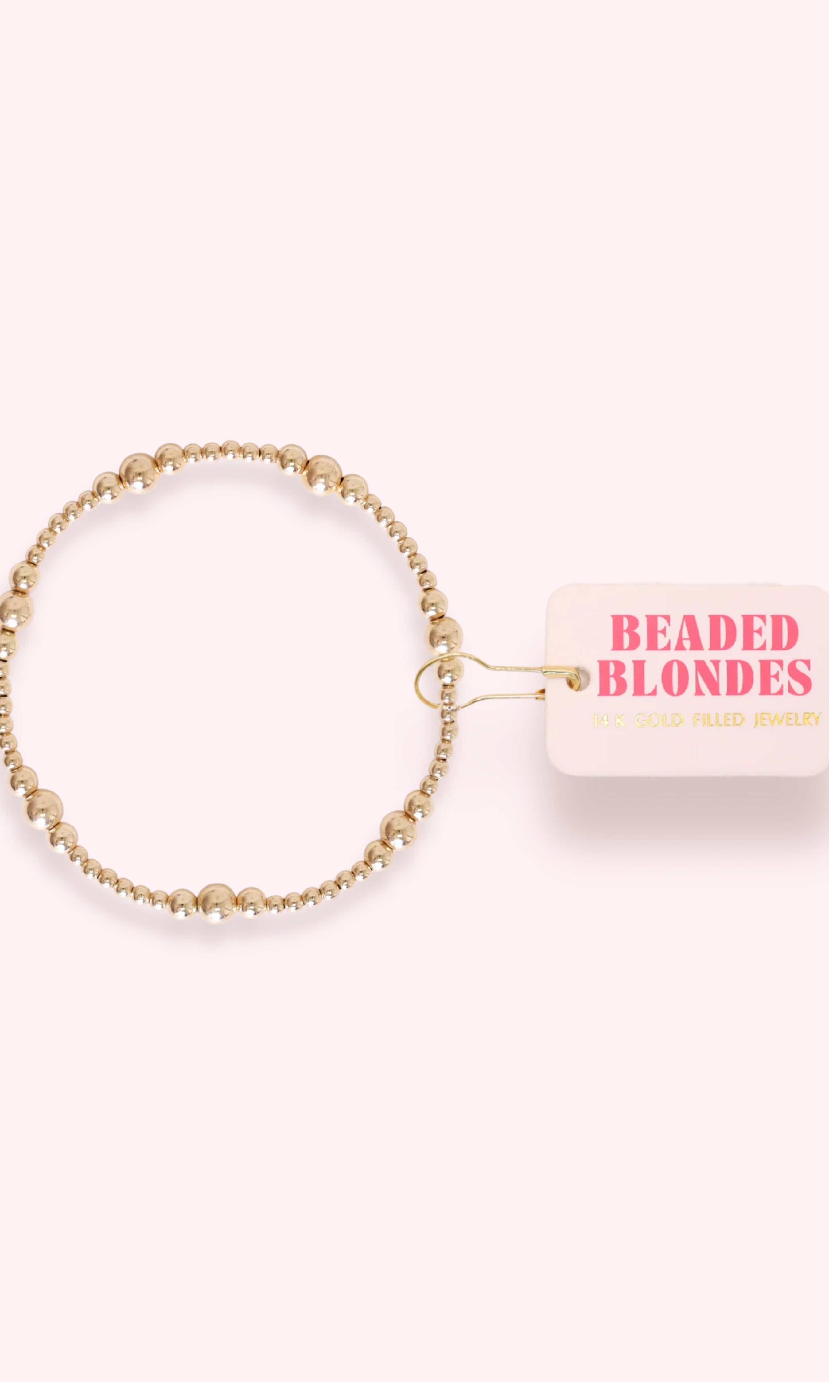 Gold beaded hair tie with 'Beaded Blondes' packaging on a white background