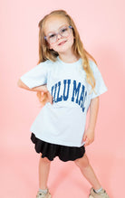 Young girl wearing a white t-shirt with blue text on a pink background