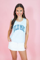 Woman wearing a light blue tank top with 'KUULU MAC' text on a pink background